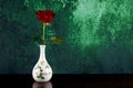 Single Red Rose in a White Ceramic Flower Vase on a Wooden Surface with Mottled Background Royalty Free Stock Photo