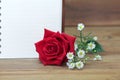 Single red roses and a white book on wooden background. Royalty Free Stock Photo