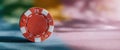 Red poker chip standing upright on colorful table Royalty Free Stock Photo