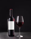 Single red wine bottle with blank label for mockup and glass of red wine on dark gray background Royalty Free Stock Photo