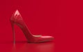 Single red womenÃ¢â¬â¢s high-heeled shoe with a pointed toe stand on the plain red background. Red pumps shoe in a classic style.