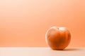 A single ripe peach fruit on minimal peach fuzz color background with copy space for text. Modern trendy tone hue shade