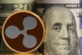 Single Ripple coin in front of bank rolls of US currency