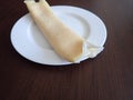 Single rolled pancake on a white plate