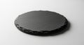 A round, dark grey slate coaster with a rough, natural edge sits on a white surface with soft lighting Royalty Free Stock Photo