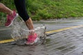 Single runner running in rain and making splash in puddle