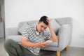 Single sad man checking mobile phone sitting on the floor in the living room at home Royalty Free Stock Photo