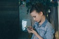 Single sad teen holding a mobile phone lamenting sitting on the bed in her bedroom with a dark light in the background Royalty Free Stock Photo