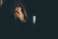 Single sad teen holding a mobile phone lamenting sitting on the bed in her bedroom with a dark light Royalty Free Stock Photo