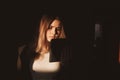 Single sad teen holding a mobile phone lamenting sitting on the bed in her bedroom with a dark light Royalty Free Stock Photo