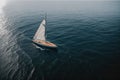 A single sailboat floating on a calm glassy sea