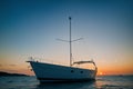 A single sailboat silhouetted against the setting sun