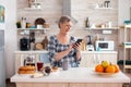 Single senior woman surfing on phone in kitchen during breakfast. Royalty Free Stock Photo