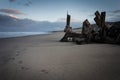 A single set of footsteps walks past the ruins of an abandoned wooden pier or jetty across the sand into the distance. Royalty Free Stock Photo