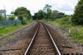 A single set of train tracks leading to a vanishing point on the horizon, the train line is cutting through rural british Royalty Free Stock Photo