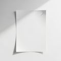 A single sheet of white paper is affixed to a smooth white wall using a small pushpin in the top Royalty Free Stock Photo