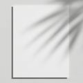 A single sheet of white paper is affixed to a smooth white wall using a small pushpin in the top Royalty Free Stock Photo