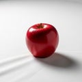 A single shiny red apple sits on a smooth white surface, casting a soft Royalty Free Stock Photo