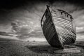 Single shipwrecked boat stranded on pebbled beach. Dungeness, England Royalty Free Stock Photo