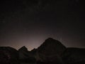 Single shooting star bursts up into the night sky above the rocky mountains