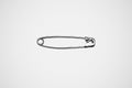 Single silver safety pin on white background