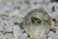 single silver shining ether coin from cryprocurrency standing in a white gravel