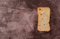 Single slice of rye melba toast on a maroon background