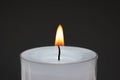 Single small white candle burning. Close up studio shot, isolated on dark background Royalty Free Stock Photo