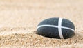 Zen Stone with White Cross Pattern on Sand Royalty Free Stock Photo