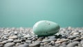 Single Smooth Turquoise Stone Resting on a Bed of Small Pebbles Against a Soft Blue Background Royalty Free Stock Photo