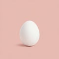 A single, smooth white egg stands upright against a soft pink background. The egg\'s Royalty Free Stock Photo