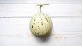 single snow leopard melon (dalmatian melon) on a white wooden table