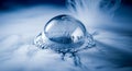 A single soap bubble resting on a surface surrounded by wisps of white smoke in a blue tinted scene Royalty Free Stock Photo