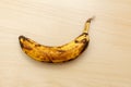 Single spoiled black banana on a wooden table.