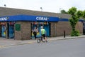 Well-known British betting shop seen together with a stationary cyclist in the foreground, looking through its window.