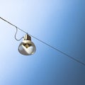 Single streetlight hanging from a metal cable on a blue background