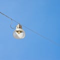 Single streetlight hanging from a metal cable on a blue background