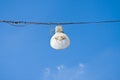 Single streetlight hanging from a metal cable on a blue background