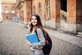 Single student walking and speak mobile phone with a university building in the background