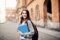 Single student walking and speak mobile phone with a university building in the background