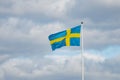 Single Swedish blue and yellow cross flag with cloudy sky background