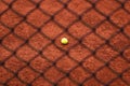 Ball on red tennis clay court behind the black iron fence - background, texture Royalty Free Stock Photo