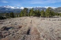 A single track trail descends into the trees and valley in front of snow covered mountain peaks.