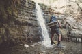 Single traveller man standing near Great Falls Shulamit falling into a shallow pond with emerald water. Ein Gedi - Nature Reserve