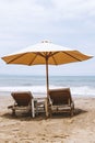 Single umbrella with two beach chairs on empty beach