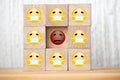 Single unhappy block and group of happy blocks symbolizing feeling lonely on wooden background