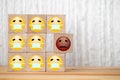 Single unhappy block and group of happy blocks symbolizing feeling lonely on wooden background