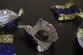 Single unwrapped chocolate bar among candy wrappers
