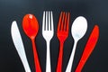 Single use red and white plastic cutlery on a leather background. Concept: Ban single use plastic Royalty Free Stock Photo