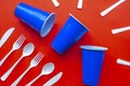 Single use white plastic cutlery and blue plastic glass on a red background. Concept: Ban single use plastic Royalty Free Stock Photo